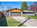 Lovely single story home with an attached garage, wooden accents, a lush lawn, and a long driveway at 12345 W 32Nd Ave, Wheat Ridge, CO 80033