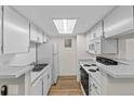 Galley kitchen with white cabinets and laminate floors at 8555 Fairmount Dr # D204, Denver, CO 80247