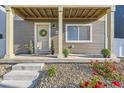 Close-up of the front porch, showing decorative plants, stone ground cover, a welcoming wreath on the door, and concrete steps at 18270 E 51St Pl, Denver, CO 80249