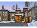 Stone-clad home with a circular window, a grand entrance, and a three-car garage amid a snow-covered landscape at 118 Gold Piece Dr, Breckenridge, CO 80424