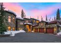 Stunning stone house featuring a red roof, three-car garage, and a driveway covered in snow at 118 Gold Piece Dr, Breckenridge, CO 80424