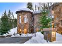 Stone house with a tower, multiple windows, and a landscaped entrance, set against a snowy mountain backdrop at 118 Gold Piece Dr, Breckenridge, CO 80424