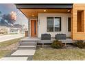 Inviting front porch with a modern design, orange door, stone accents and manicured landscaping at 3000 S Elati St, Englewood, CO 80110
