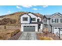Two story home boasts white siding, dark shutters, and a gray garage door, set against mountain views at 1044 Oleander St, Castle Rock, CO 80109