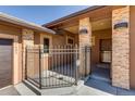 View of front entrance featuring stone pillars and covered walkway enclosed by a wrought iron fence at 7482 Sleeping Bear Trl, Littleton, CO 80125