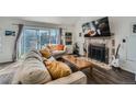 Bright living room with dark wood floors, brick fireplace, and sliding doors to the backyard at 10064 Owens St, Broomfield, CO 80021