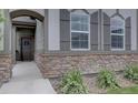 Home entrance featuring a stone facade, arched doorway, and manicured landscaping with a concrete walkway at 6612 N Ceylon St, Denver, CO 80249