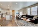 Open-concept living room featuring wood floors, large windows, a comfortable sofa, and access to the kitchen at 6612 N Ceylon St, Denver, CO 80249
