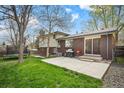 Spacious backyard features a concrete patio, lush lawn, and mature trees, creating an inviting outdoor space at 1492 S Dudley St, Lakewood, CO 80232