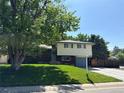 Attractive home with lush front lawn, mature trees, and convenient driveway, offering a welcoming curb appeal at 1492 S Dudley St, Lakewood, CO 80232