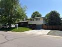Lovely split-level home with a lush front lawn and mature trees, showcasing the exterior and curb appeal at 1492 S Dudley St, Lakewood, CO 80232