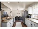 Bright kitchen features stainless appliances, white cabinets, granite counters, and adjoining dining area at 1492 S Dudley St, Lakewood, CO 80232