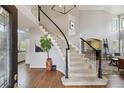 Elegant foyer showcasing a curved staircase with wrought iron railings, hardwood floors, and a soaring ceiling at 11302 E Ida Ct, Englewood, CO 80111