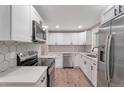 Modern kitchen featuring stainless steel appliances, white cabinets, quartz countertops and a tiled backsplash at 8280 Auburn Ln, Westminster, CO 80031