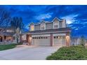 Charming two-story home with three-car garage and brick accents at twilight at 6973 Daventry Pl, Castle Pines, CO 80108