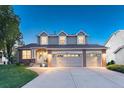 Inviting two-story home featuring a brick facade and a spacious three-car garage at 6973 Daventry Pl, Castle Pines, CO 80108