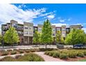 Modern building facade featuring balconies and well-maintained landscaping, with lush green trees and colorful shrubbery at 7700 E 29Th Ave # 404, Denver, CO 80238