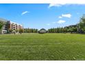Expansive green park with neatly manicured lawns, trees, and an outdoor amphitheater in the distance under a blue sky at 7700 E 29Th Ave # 404, Denver, CO 80238