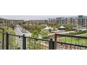 Balcony view overlooking a neighborhood park, a street with parked cars, and apartment buildings at 7700 E 29Th Ave # 404, Denver, CO 80238