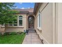Inviting entrance with an arched doorway, decorative windows, and a pathway lined with tasteful landscaping at 4775 S Anaheim Ct, Aurora, CO 80015