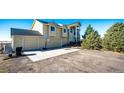 View of a yellow home with a two-car garage, basketball hoop, and a long driveway in rural surroundings at 7440 S Shenandoah Dr, Elizabeth, CO 80107