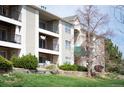 Multi-level condo building with balconies, manicured landscaping, and mature trees at 12158 W Dorado Pl # 205, Littleton, CO 80127