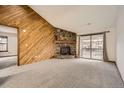 Spacious living room with stone fireplace, wood accent wall, and access to an outdoor balcony at 7790 W 87Th Dr # H, Arvada, CO 80005