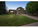 Charming two-story home featuring a lush green lawn, mature trees and an attached two-car garage at 9361 Crestmore Way, Littleton, CO 80126