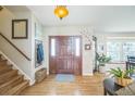 Inviting foyer with hardwood floors, stylish light fixture, and staircase with wooden banister at 9361 Crestmore Way, Littleton, CO 80126