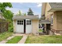 Detached garage with weathered white doors, showing potential for storage or a workshop space at 1551 S University Blvd, Denver, CO 80210