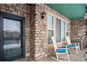 Charming front porch featuring a stone facade and two rocking chairs, creating a cozy outdoor space at 643 S Norfolk Way, Aurora, CO 80017