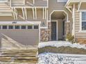 Two-car garage with stone entryway and snowy landscaping at 10767 Mountshire Cir, Highlands Ranch, CO 80126