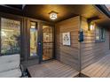 Inviting covered front porch and front door area with wood decking, decorative lighting, and cabin signage at 8140 Lightening View Dr, Parker, CO 80134