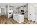 Modern kitchen with stainless steel appliances, a center island, light grey cabinets, and hardwood floors at 9465 Yampa St, Commerce City, CO 80022