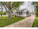 Well-maintained home featuring a lush lawn, mature trees, and a detached garage at 2634 S Humboldt St, Denver, CO 80210
