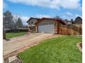 View of the home featuring an attached two-car garage, driveway and mature lawn and landscaping at 85 Yank Way, Lakewood, CO 80228