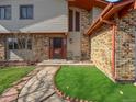 Close up of the front entryway featuring a well-maintained lawn, pathway, and brick accents at 85 Yank Way, Lakewood, CO 80228