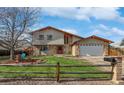 Charming exterior view of a two-story home with a well-manicured lawn and a rustic wooden fence at 85 Yank Way, Lakewood, CO 80228