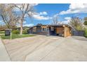 Single-story home featuring black brick, clean landscaping, concrete driveway, and covered outdoor seating at 6170 Estes Ct, Arvada, CO 80004