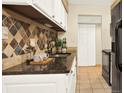 Kitchen with stylish backsplash, granite counters and white cabinets at 7755 E Quincy Ave # 206, Denver, CO 80237