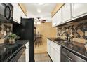 Galley kitchen featuring black appliances, white cabinets, and dining nook at 7755 E Quincy Ave # 206, Denver, CO 80237
