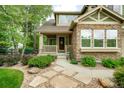 Inviting front porch and walkway, complemented by a stone exterior and lush landscaping at 15348 W 75Th Pl, Arvada, CO 80007