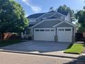 Two-story home boasts a gray exterior, a two-car garage, charming porch, and mature landscaping at 6358 S Miller Way, Littleton, CO 80127