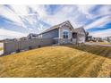 Side view of a house with gray siding, landscaping, and a fenced yard at 1680 Rivergate Way, Berthoud, CO 80513