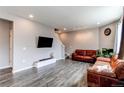 Open living room with hardwood floors, a large television, and cozy leather couches at 13921 Scarlet Sage Ln, Parker, CO 80134
