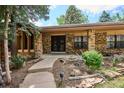 Inviting brick facade with unique stone accents and landscaped garden beds, creating a warm welcome at 7577 S Pierce Way, Littleton, CO 80128