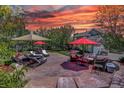 Expansive stamped concrete patio with an outdoor seating area, umbrellas, and lush landscaping at 20113 Edinborough Ct, Parker, CO 80138