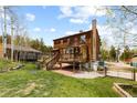 Charming wooden home featuring an outdoor deck, brick chimney, and a spacious lawn at 8600 S Warhawk Rd, Conifer, CO 80433