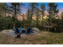 Serene outdoor fire pit area with seating, surrounded by towering trees and mountain views at 11348 Ranch Elsie Rd, Golden, CO 80403