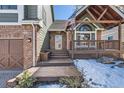 Welcoming covered entry porch with an American flag, leading to the front door of this charming residence at 27 Buckthorn Dr, Littleton, CO 80127